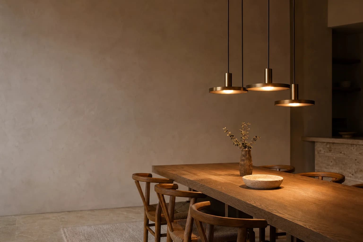 Warm brass and black pendant lights lit low over an oak dining table — Pendants & Chandeliers by REO